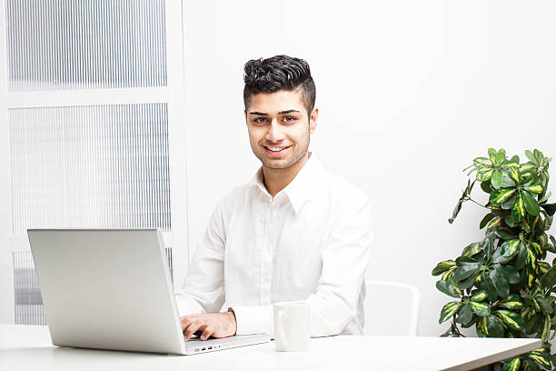 Young Asian Indian Businessman working on laptop in office
